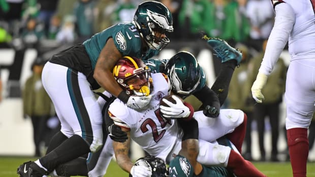 Philadelphia Eagles defenders tackle a Washington Commanders ball-carrier.